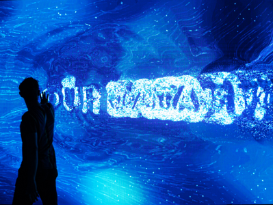 A person in front of a wall with a blue projection