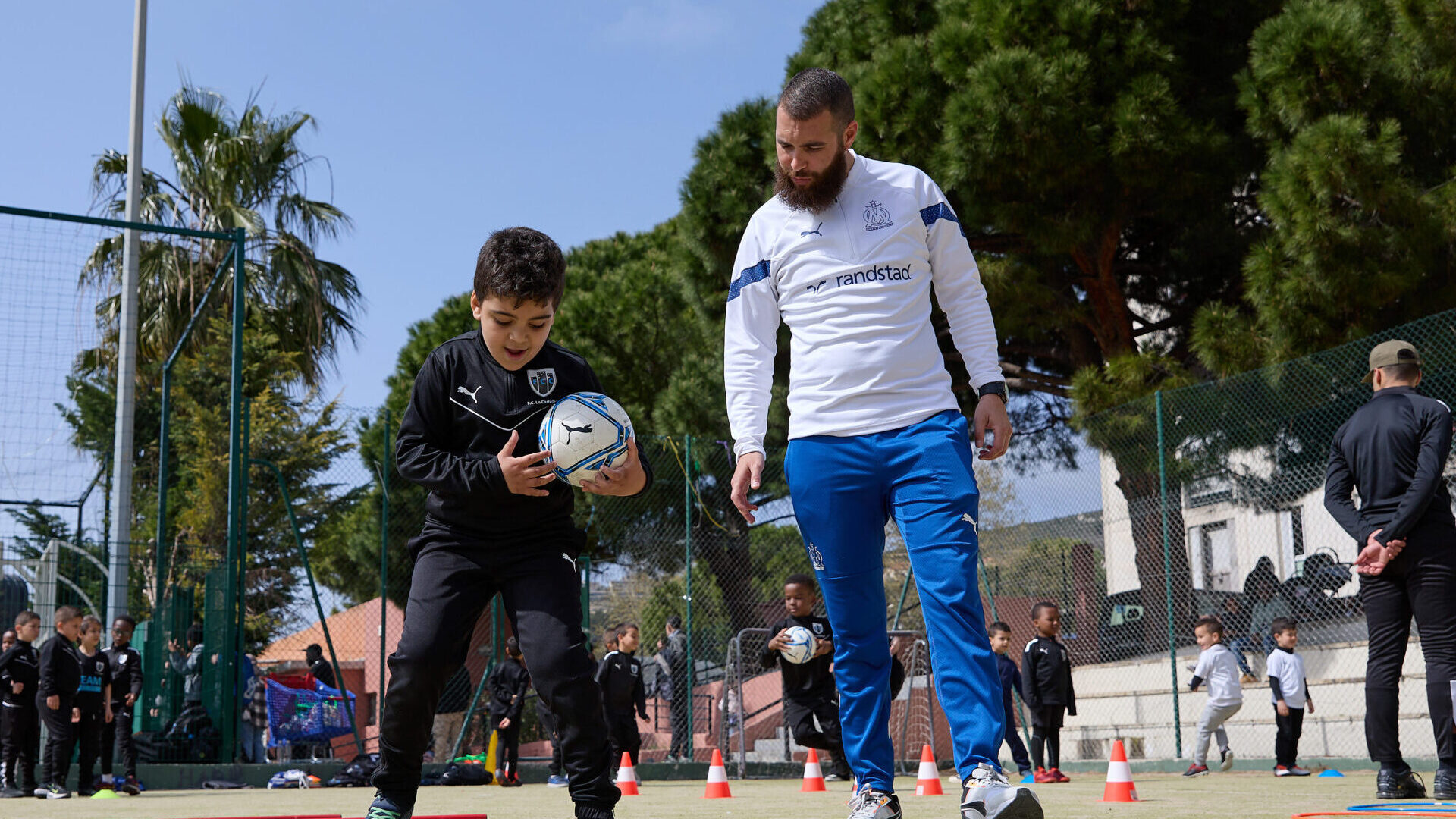 Olympique de Marseille coach working on drills with a young FC La Castellane player